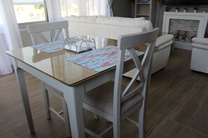 En matplats med ett glasbord, vita stolar och en vit soffa.