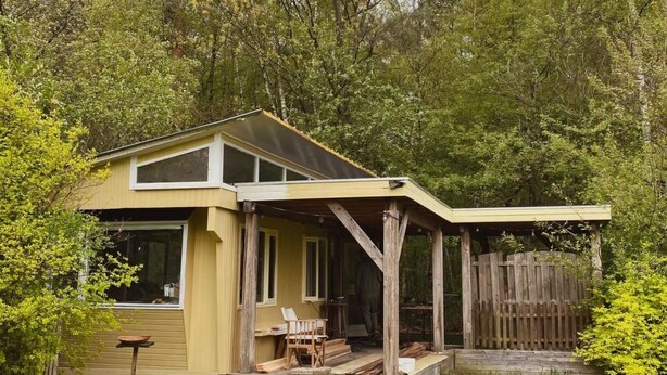 Einbungalow mit überdachter Veranda und umzäuntem Garten.