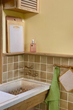 A kitchen with a wooden countertop, a sink with a vintage faucet, and a green towel hanging on a rack. - Camping Ont Moeten - Rumi by Interhome (Rekken)