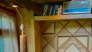 Eine gemütliche Sitzecke mit gepolstertem Sitz, einer Hängelampe und einem Bücherregal mit Büchern und einem Radio.