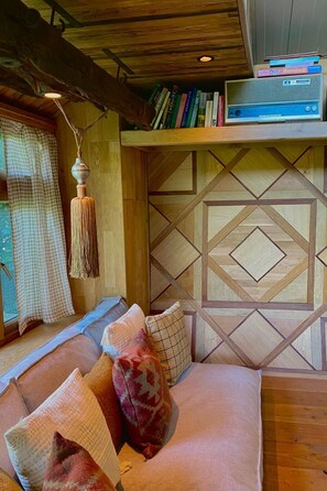 A cozy seating area with a cushioned bench, a hanging lamp, and a bookshelf with books and a radio. - Camping Ont Moeten - Rumi by Interhome (Rekken)