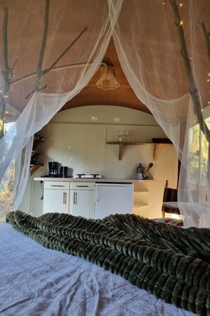 A cozy bedroom with a canopy bed, a kitchenette with cabinets, and a dining area. - Camping Ont Moeten - T piept zo by Interhome (Rekken)