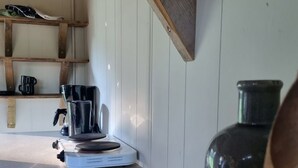 Une cuisine équipée d’une machine à café, d’un grand pot en céramique et d’une cuillère en bois posée sur le comptoir.