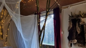 Ein gemütliches Zimmer mit einem Himmelsbett, einer Holzbank und einer rustikalen Wanddekoration.