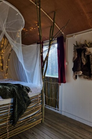 A cozy room with a bed under a canopy, a wooden bench, and a rustic wall decoration. - Camping Ont Moeten - T piept zo by Interhome (Rekken)