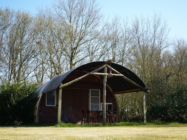 A rustic wooden cabin with a large porch and a metal roof, surrounded by trees. - Camping Ont Moeten - Romney Lodge by Interhome (Rekken)