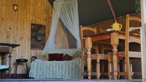 Ein gemütliches Zimmer mit Holzvertäfelung, einem Himmelbett, einem Tisch, Stühlen und einer hängenden Pflanze.
