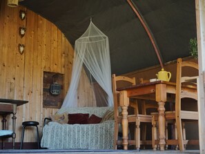 A cozy room with a wooden interior, a bed with a canopy, a table, chairs, and a hanging plant. - Camping Ont Moeten - Romney Lodge by Interhome (Rekken)