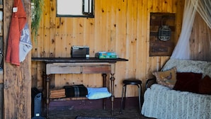 Ein Zimmer mit Holzboden, einem Tisch, Stühlen, einem Bett und einem Fenster.