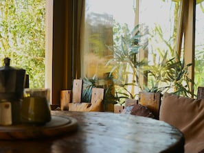 A rustic wooden table with a teapot and cup, a wooden chair, and a large window with a view of greenery. - Camping Ont Moeten - Waterflow by Interhome (Rekken)