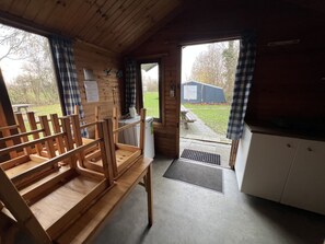 Puinen sisustus, jossa on penkki, uloskäyntiovi ja näkymä ruohikkoiselle alueelle.