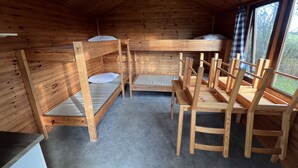 Una cabana de fusta amb lliteres, un escriptori i cadires.