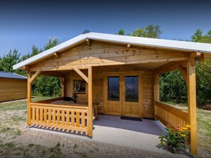 A wooden cabin with a covered porch, a small deck, and a window.