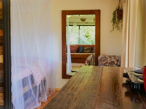 Una stanza con un tavolo di legno, un letto con zanzariera, una panca e una pianta pensile.