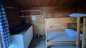 Une petite cabane en bois avec des lits superposés, un bureau et une étagère.