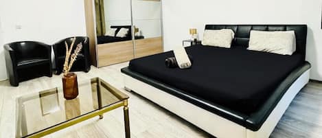 A bedroom with a bed, a bedside table, a mirror, a wardrobe, and a chair.