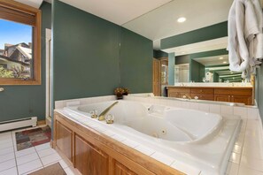 Ein Badezimmer mit einer großen Badewanne, einem Holzbadezimmer-Möbel und einem Spiegel.