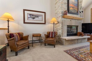 A cozy living room with leather armchairs, a fireplace, a framed picture, and a television. - Ironwood 4 - Ski In Ski Out & Right Next to the Gondolas! EZCancel (Steamboat Springs)