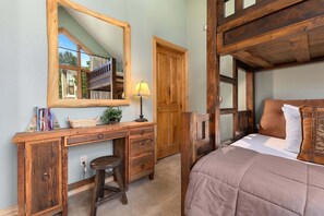 Ein Schlafzimmer mit einem Holzbett, einem Schreibtisch mit Stuhl, einem Spiegel und einer Lampe.