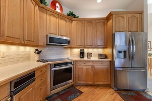 A kitchen with wooden cabinets, stainless steel appliances, and a built-in oven. - Ironwood 4 - Ski In Ski Out & Right Next to the Gondolas! EZCancel (Steamboat Springs)