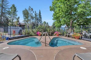 A pool area with two pools, surrounded by a fence, and equipped with lounge chairs. - Ironwood 4 - Ski In Ski Out & Right Next to the Gondolas! EZCancel (Steamboat Springs)