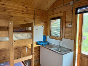 Una cabina compatta con un letto a castello, angolo cottura con lavello e finestra con persiane.