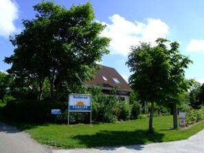 Cartell de Sudersø Camping amb una casa al fons.