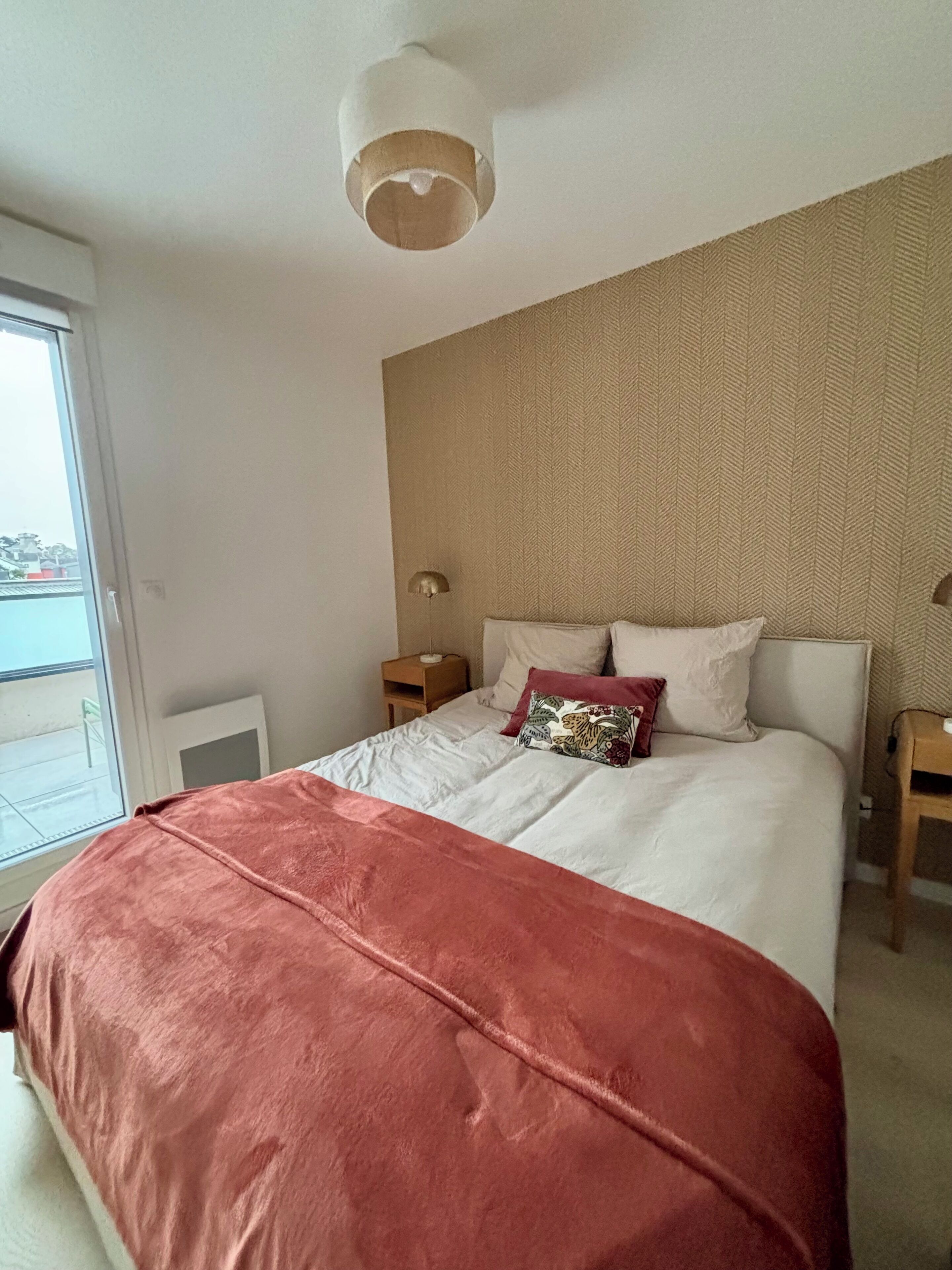 Une chambre à coucher avec un grand lit, une fenêtre et un luminaire au plafond.