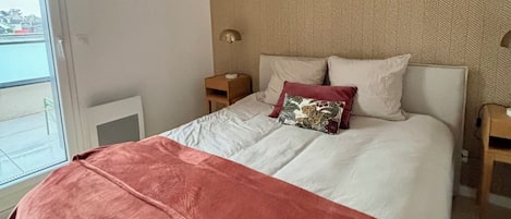 A bedroom with a large bed, a window, and a ceiling light fixture.