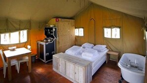 A tented accommodation with a bed, a small desk, a chair, a sink, and a window. - Outdoors Holten - Romantic Safaritent bad by Interhome (Holten)