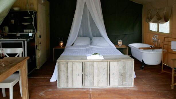 A tented accommodation with a bed, a table, a sink, and a small kitchenette. - Outdoors Holten - Romantic Safaritent bad by Interhome (Holten)