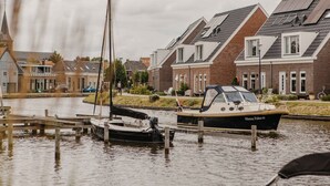 A canal with boats docked, surrounded by residential buildings with pitched roofs.