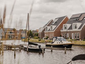 A canal with boats docked, surrounded by residential buildings with pitched roofs.