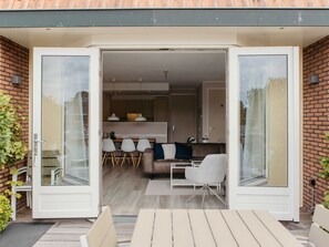 Moderni, avoimen pohjaratkaisun omaava olohuone, jossa on keittiö, ruokailutila ja patio ulkokalusteineen.