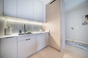 Una cocina moderna con muebles blancos, un lavamanos de acero inoxidable y un respuesto de azulejos.