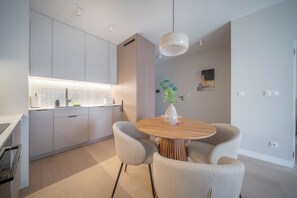 A modern kitchen with white cabinets, a round wooden dining table, and two grey chairs. - Kierbedzia Beige Elagant, Mokotow, Warsaw (Warszawa)