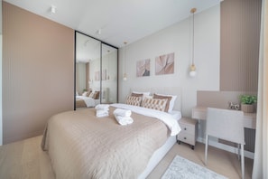 A modern bedroom with a large bed, bedside tables, a mirror, and artwork on the wall. - Kierbedzia Beige Elagant, Mokotow, Warsaw (Warszawa)