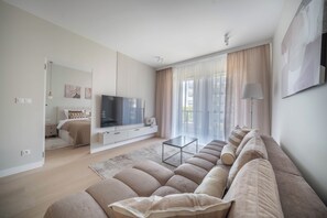 A modern living room with a large flat-screen TV, a sofa, and a coffee table. - Kierbedzia Beige Elagant, Mokotow, Warsaw (Warszawa)