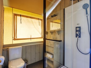 A compact bathroom with a toilet, a shower, and a window. - De Glamping - Duo Lodge | 12p by Interhome (Zeewolde)