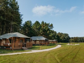 A row of cabins with wooden decks and a grassy field in the background. - De Glamping - Glamping Lodge | 6p by Interhome (Zeewolde)