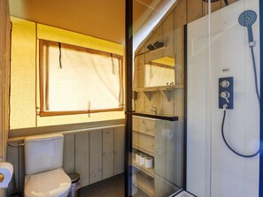 A compact bathroom with a toilet, a shower, and a window. - De Glamping - Combo Lodge | 5 p lodge + 2 p tent by Interhome (Zeewolde)