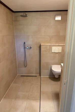 A bathroom with a shower, toilet, and a wall-mounted towel dispenser. - Camping Ont Moeten - Hallertau by Interhome (Rekken)