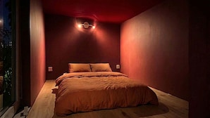 Ein Schlafzimmer mit einem Bett, Holzboden und einem Fenster.