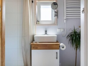 A bathroom with a white sink, a mirror, a towel, and a toilet. - De Glamping - Gele Tiny House | 5p by Interhome (Zeewolde)