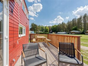 A red building with a deck, two chairs, and a table. - De Glamping - Tiny House rood | 5p by Interhome (Zeewolde)