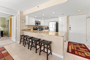 A modern kitchen with white cabinets, stainless steel appliances, and a granite countertop. - S Hampton 1206 3 Br Oceanview in Kingston, Pool (Myrtle Beach)