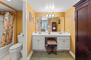 Een badkamer met een wit toilet, een wit wastafel met een spiegel erboven en een houten kastje.