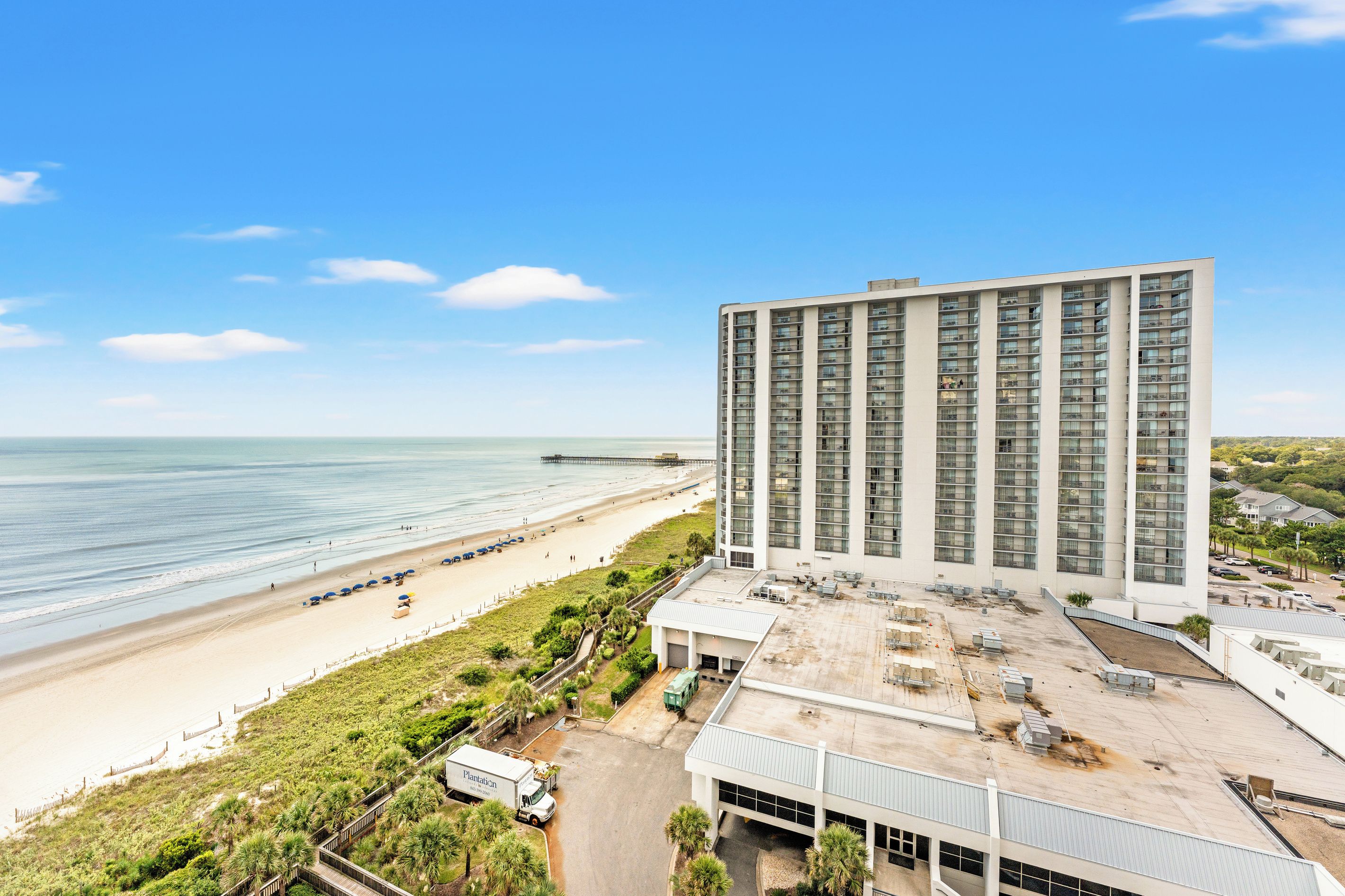 A high-rise hotel with a beach view, a parking area, and a dock.