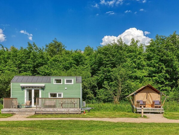 A green mobile home with a porch and a separate cabin with a porch. - De Glamping - Tiny Safari Groen | 8p by Interhome (Zeewolde)