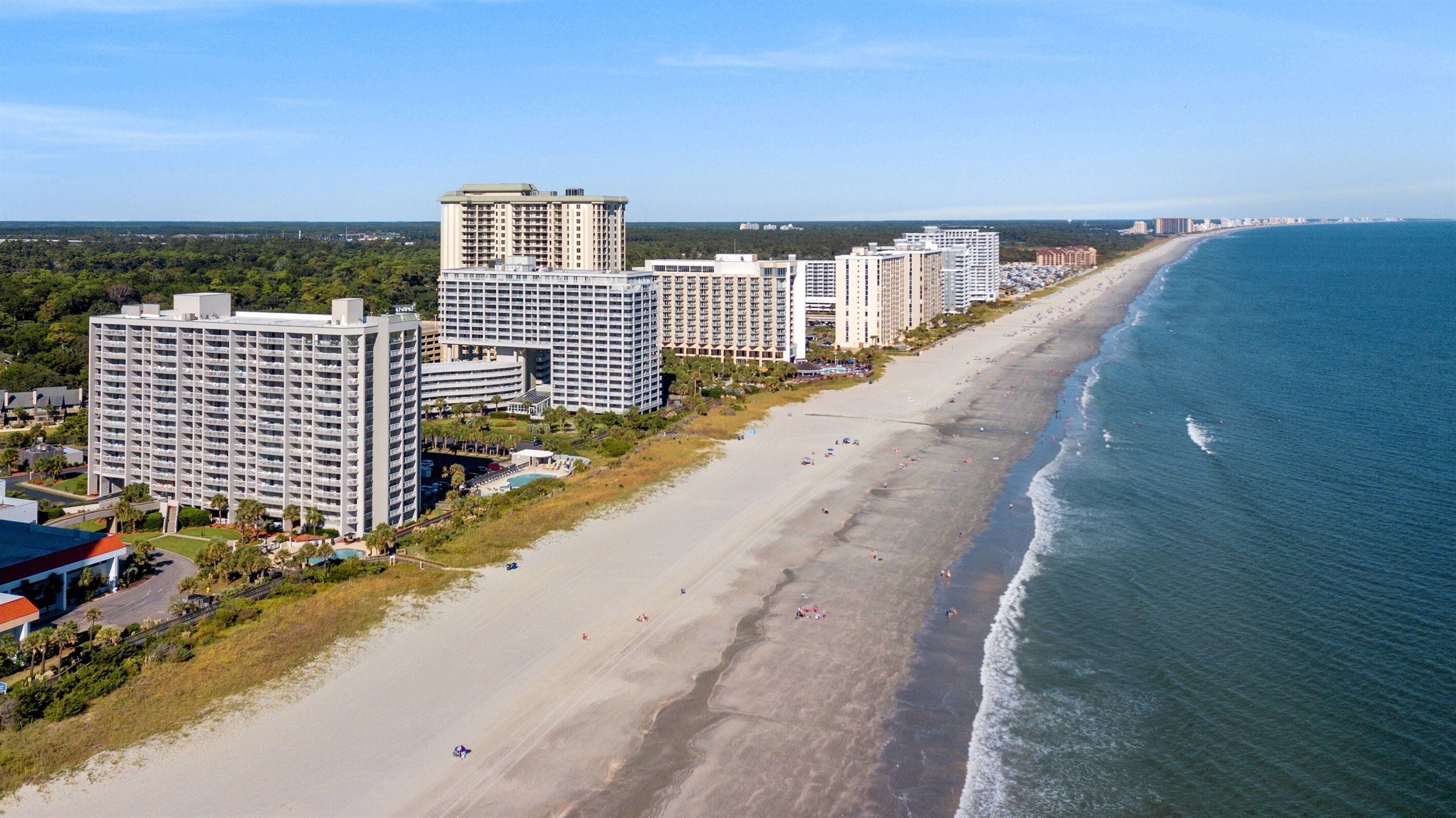 Eine Küstenstadt mit Hochhotels entlang eines Sandstrandes.